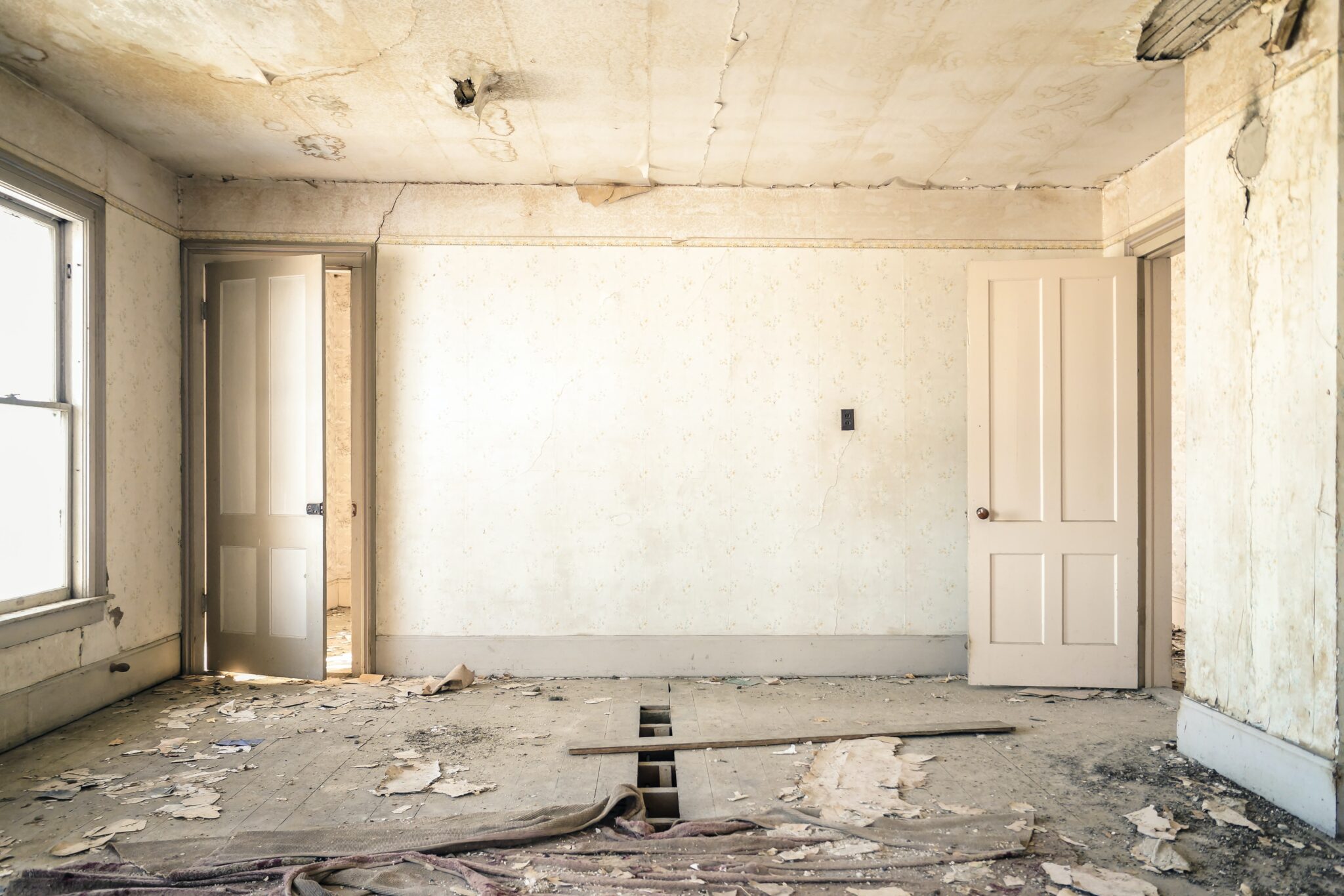 A room that is falling apart with old white décor.