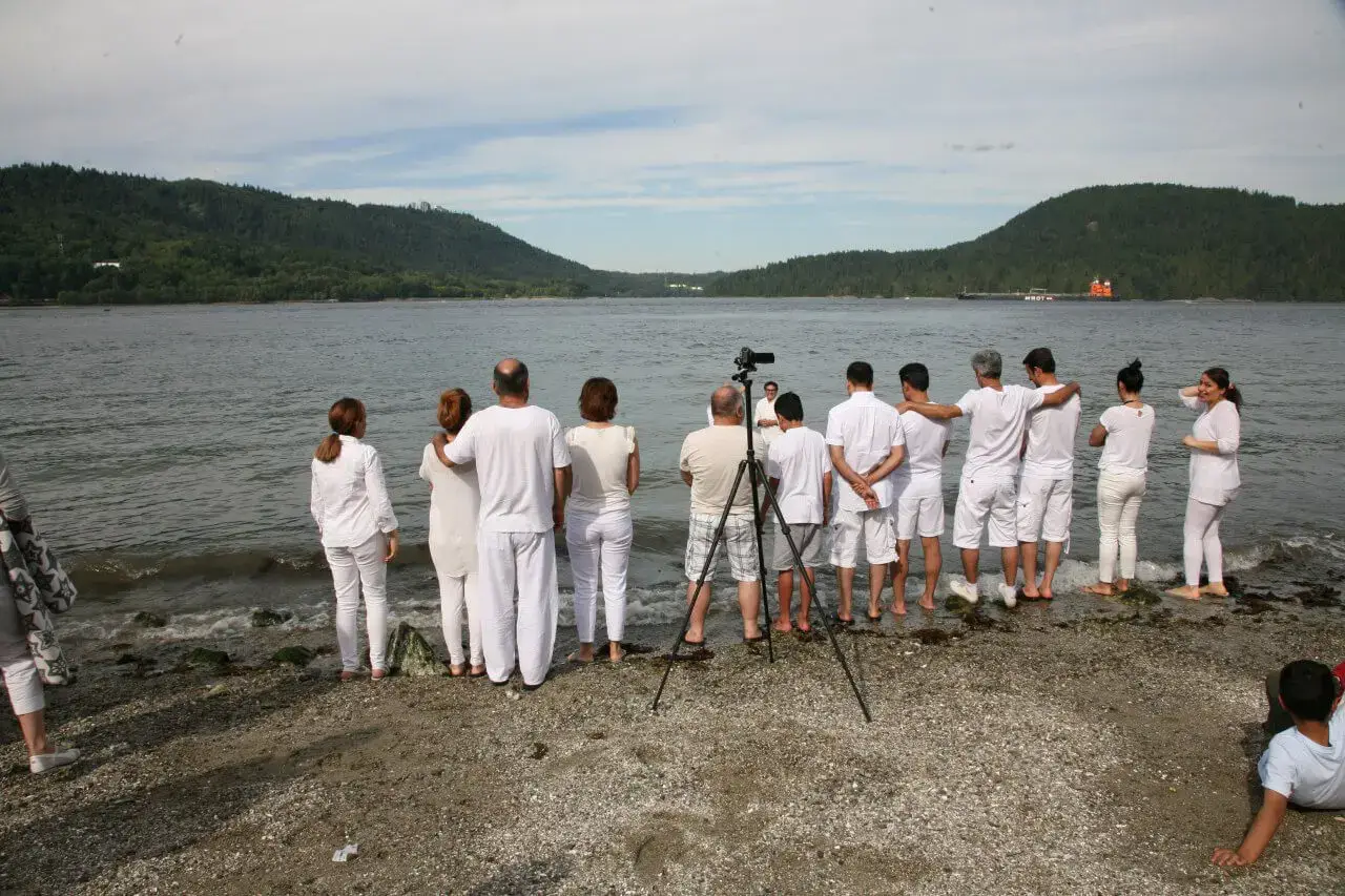 Congregants at North Shore Alliance Church standing on the shore. Everyone is wearing white and waiting to be baptized.