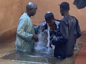 Two men are baptizing a third man