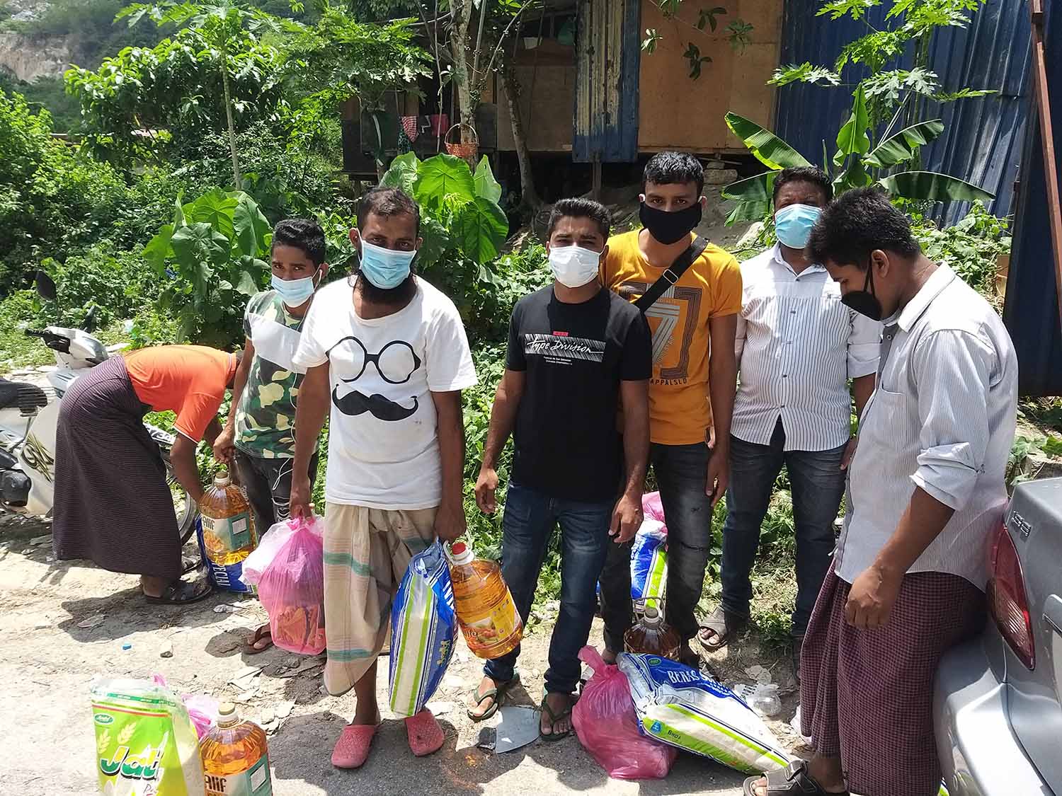Rohingya men receiving food aid.