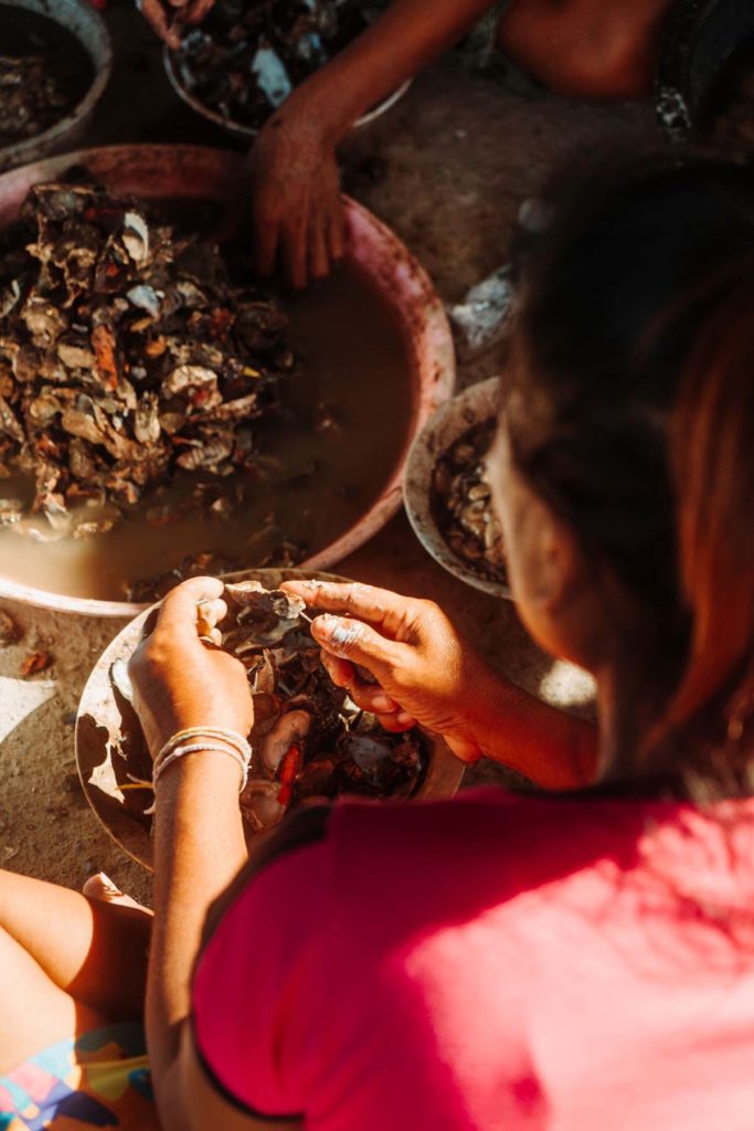 A view over the shoulder of an Urak Lawaoi woman as she prepares seafood with a knife.