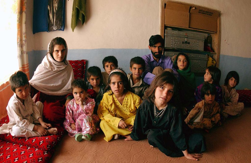 Large Pashtun family sitting on the floor of a home.