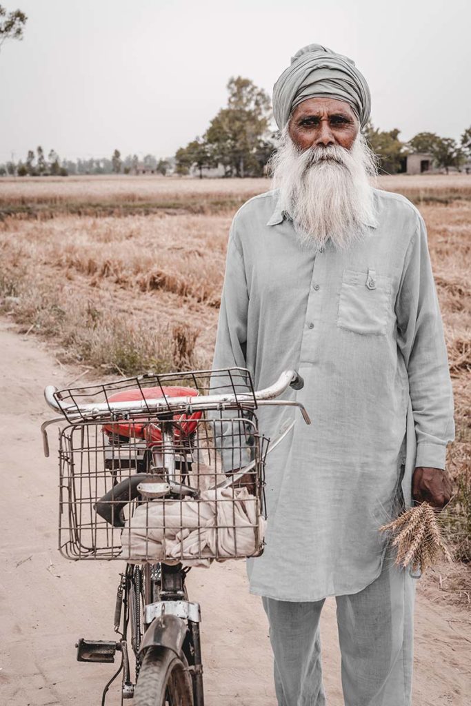 Arain man standing with a bicycle.